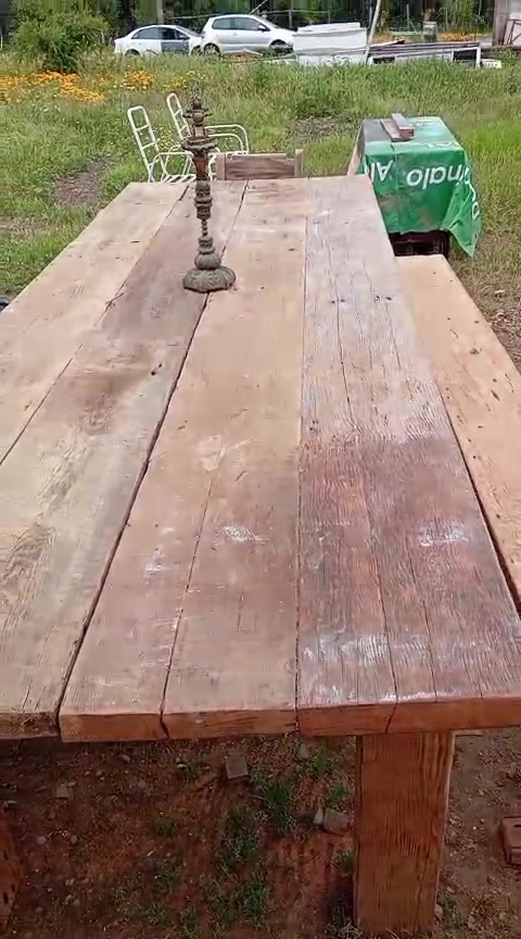 Un comedor de tablones visto de punta a punta, con el pasto y los cerros de fondo